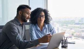 Manager and employee over laptop in corporate office