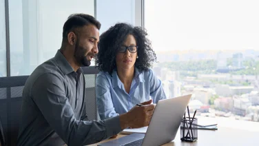 Manager and employee over laptop in corporate office