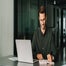 Smiling young man working at desk in office with laptop