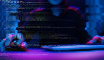 Figure at computer with code on screen