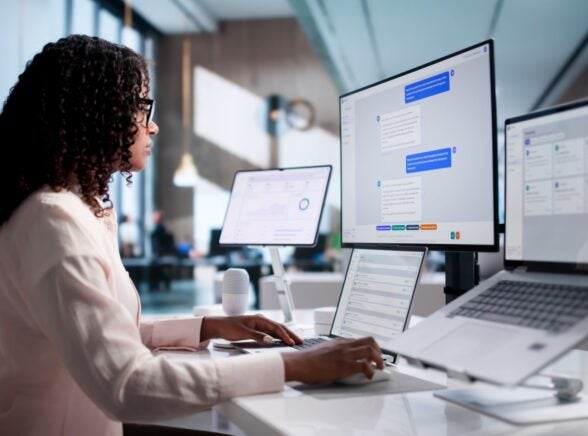 Woman working with AI on monitor and laptop