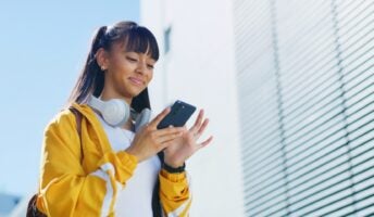 Young girl on phone smiling outside building