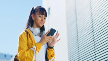 Young girl on phone smiling outside building