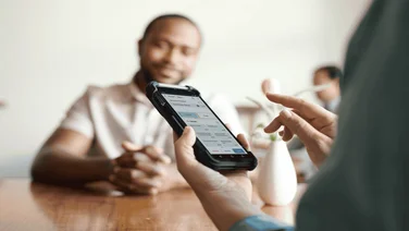 Hands holding a phone with unified commerce software