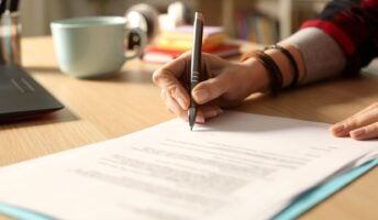 Hand signing contract on desk