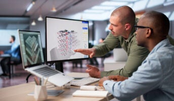 Office workers using project management software on laptop
