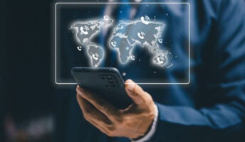 Business professional using a smartphone with a world map and phone icons