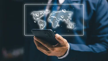 Business professional using a smartphone with a world map and phone icons